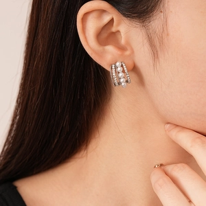 Dettaglio degli orecchini a C multistrato con perle e strass su orecchio di modella