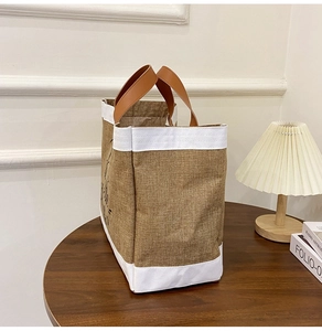 Detailed shot of a linen tote bag with PU leather handles on a rustic wooden table