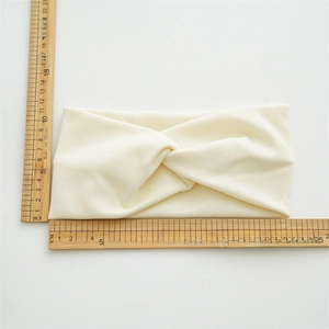 Detailed view of cream knit headband dimensions measuring 21cm by 10cm on white background