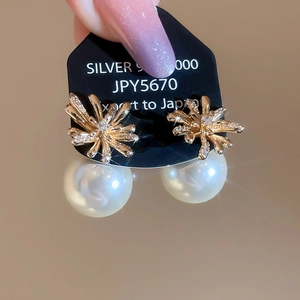 Close-up of gold fireworks stud earring with zircon inlay and large white hanging pearl