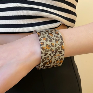 Detailed view of acrylic leopard print cuff bracelet with golden texture and retro style