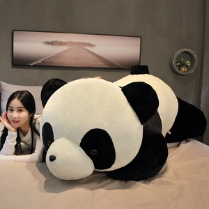 Gros plan d'un oreiller panda géant en peluche sur un lit, montrant la texture douce