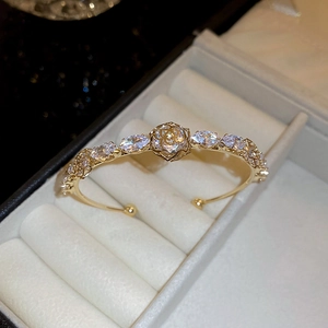 Close-up of a 14k gold-plated open bangle featuring a zircon flower and teardrop accents