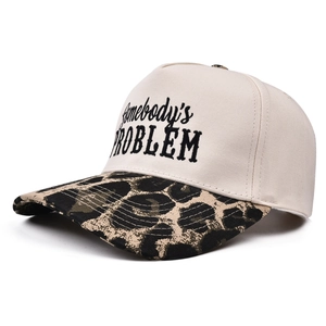 Detail of Somebody's Problem embroidery on ivory canvas with leopard print brim trucker hat
