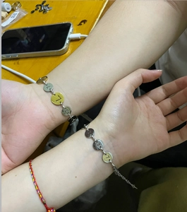 Dettaglio di bracciali a catena in acciaio inossidabile argento e oro indossati ai polsi