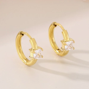 Detailed close-up of golden huggie earrings featuring a square-cut clear crystal stone