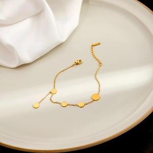Detail of gold geometric round disc bracelet with lobster clasp on ceramic tray