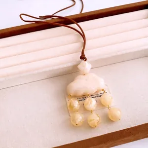 Artistic cloud resin pendant necklace with cream beads on brown cord in jewelry tray