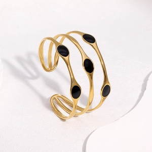 Detailed view of multilayer 18k gold plated open bangle with black enamel oval charms