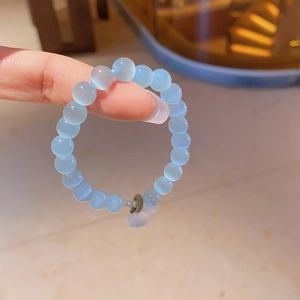 Close-up of light blue cat-eye beaded bracelet with a small metal clasp and pendant