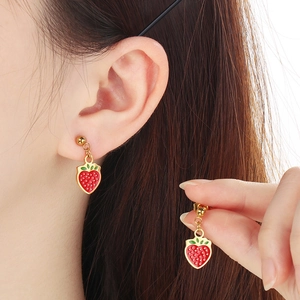 Detail of red enamel strawberry pendant necklace on model with golden metal finish