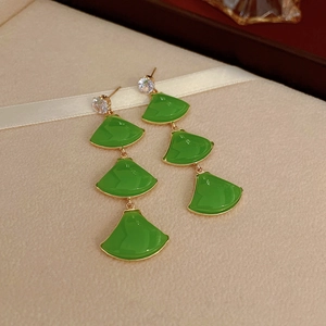 Détail de boucles d'oreilles pendantes vintage vertes en éventail sur boîte à bijoux