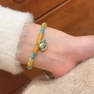 Macro detail of hand-woven turquoise rope bracelet with enamel pony pendant and gold accents