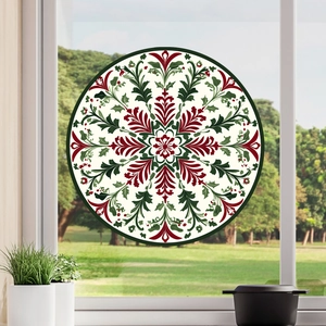 Macro detail of round mandala window decal with red and green festive plant motifs
