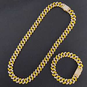 Detailed macro view of gold plated Cuban link chain set with yellow enamel and crystals