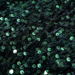 Detailed macro shot of dark green sequin fabric with dense round metallic sparkles