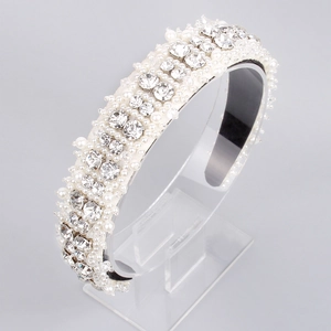 Macro view of a white pearl and rhinestone headband on a clear display stand