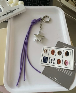 Detail view of a Y2K style star pendant with purple woven rope on a metal buckle