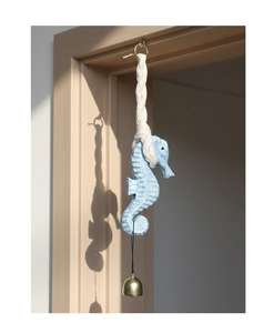 Detail of light blue textured seahorse ornament with cotton rope and golden bell
