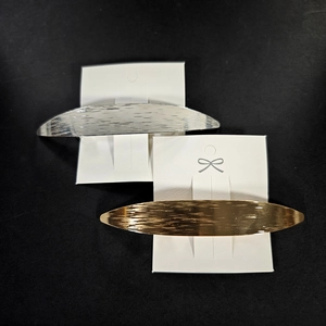 Pair of minimalist gold and silver metal hair clips with brushed texture on white card