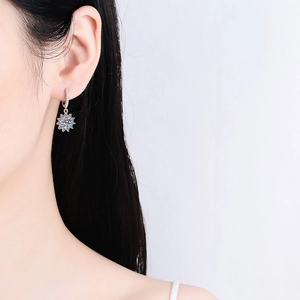 Elegant silver sunflower drop earrings with sparkling moissanite stones on a female model