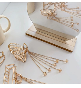 Detail of gold butterfly and square hair claws with elegant pearl tassel charms