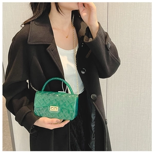 Close-up of green quilted jelly bag with gold chain and metal lock worn by a model