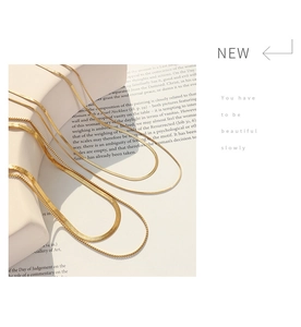 Detail of layered gold snake chains displayed on minimalist props with a modern aesthetic