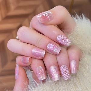 Pink bow press-on nails with plaid patterns and cat eye finish on a hand model
