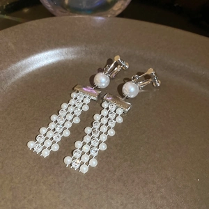 Close-up of silver tassel clip-on earrings with white pearls and clear rhinestones