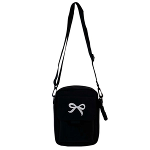 Detail of black canvas crossbody bag featuring a white bow embroidery and adjustable strap