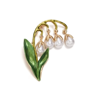 Detail of lily of the valley brooch with white pearls and green enamel on golden alloy