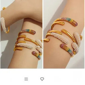 Détail d'un bracelet manchette plaqué or 18k avec perles blanches et strass arc-en-ciel