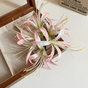 Detail of pink and white gradient silk flower hair clip on a wooden jewelry box edge
