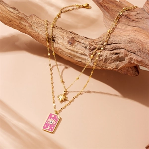 Detailed shot of double layer gold celestial necklace with pink tarot eye pendant on wood