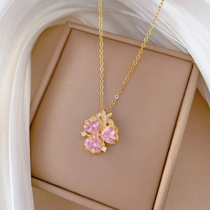 Luxurious gold clover necklace with pink heart crystals on a jewelry box display
