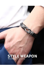 Macro view of men's black woven leather bracelet with polished silver steel metal knot