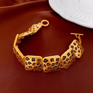 Détail d'un bracelet doré vintage léopard avec cristaux orange sur fond de velours