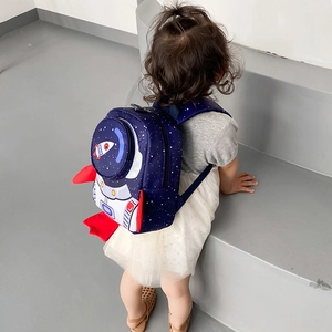Detail of blue rocket toddler backpack with starry pattern and red fins on a child