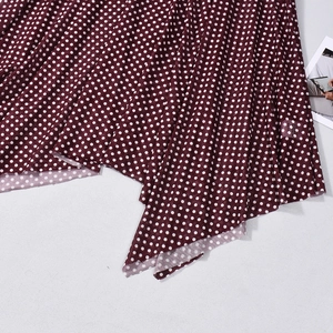 Detail of burgundy polka dot mesh fabric featuring asymmetrical wavy hemline design