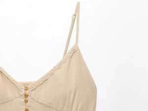 Détail d'une robe en lin avec bordure en dentelle, boutons en bois et bretelles