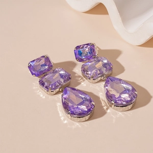 Dettaglio di orecchini di lusso in cristallo viola con pietre quadrate e a goccia