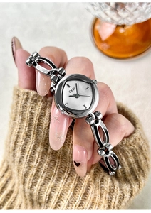 Silver bracelet watch with a hollow link band styled on a cozy knit sweater sleeve