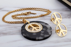 Detail view of vintage gold peace sign jewelry set with acrylic marble texture and crystals