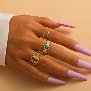 Close-up of gold titanium rings set featuring Cuban chain and turquoise bead details