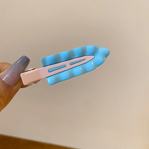 Detail of sky blue and light pink wavy side hair clip with minimalist resin finish