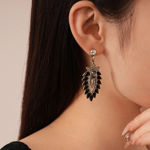 Detail of vintage flower earrings with dark leaves and crystals on model's ear