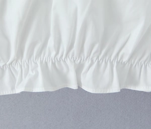 Detailed close-up of white cotton fabric texture with elastic ruffled hem design