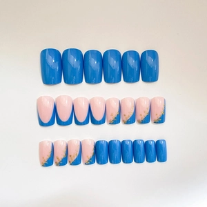 Short square blue and nude press-on nails with shiny gold foil accents on white background