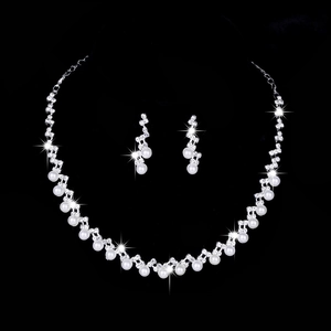 Silver bridal jewelry set with white pearls and sparkling rhinestones on black backdrop